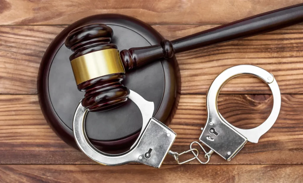 Gavel with stand and handcuffs on the wooden background. Top view.