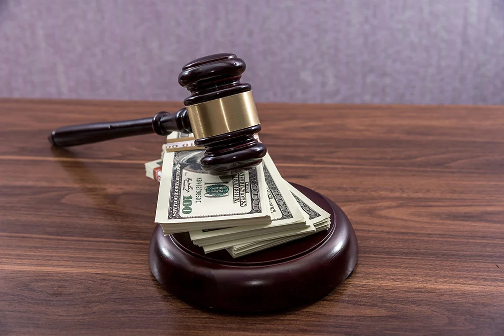Judge gavel with dollars on wooden table
